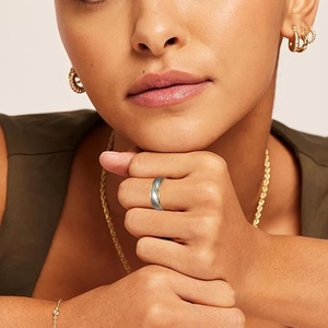 Close-up of gold and silver diagonal striped ring worn by a model in a fashion setting