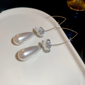 Détail des boucles d'oreilles perles gouttes avec fleurs en zircon sur un plat en porcelaine
