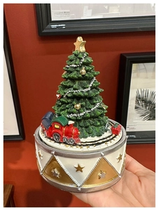 Detailed view of a green Christmas tree music box with a rotating miniature red train