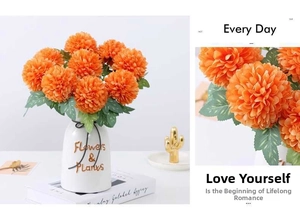 Detail of orange ping pong chrysanthemum silk flowers in white ceramic vase for home decor