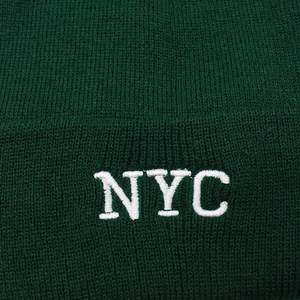 Detail shot of the NYC embroidery and thick knit texture on a dark green beanie