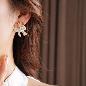 Close-up of elegant bow stud earrings with white enamel and sparkling zircon teardrop charms