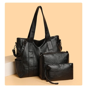 Three-piece black PU leather tote bag set including handbag and small pouch on white pedestals
