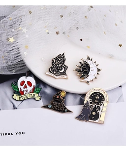 Detail of gothic enamel pins featuring skull, celestial moon, and wizard hat designs