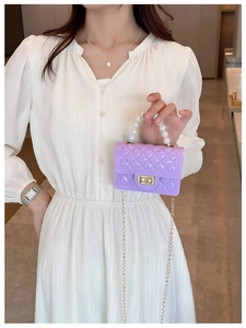 Detail of purple quilted jelly handbag featuring pearl handle and gold chain strap