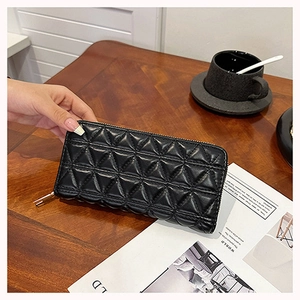 Macro detail of black quilted long wallet with triangle stitching and zipper closure