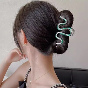 Detail showing a silver snake hair claw clip with green enamel on a model's hair