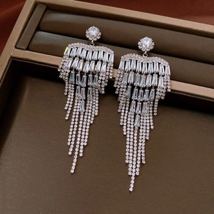 Close-up of silver tassel bow earrings with sparkling rhinestones in a dark jewelry box