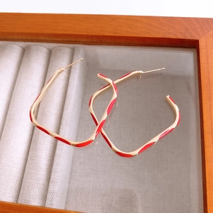 Detailed view of red and gold geometric enamel earrings in a luxury display case