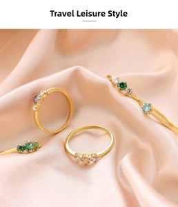 Detail of four gold-plated alloy rings with emerald and sapphire gemstones on silk