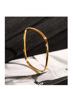 Detailed macro view of a minimalist square gold bangle featuring a tiny white zircon inlay