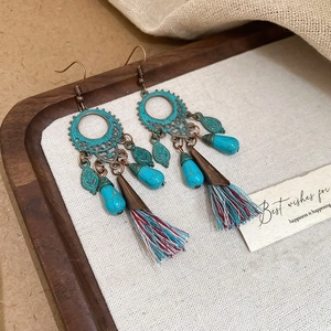 Detail of vintage bohemian earrings featuring turquoise beads and colorful cotton tassels