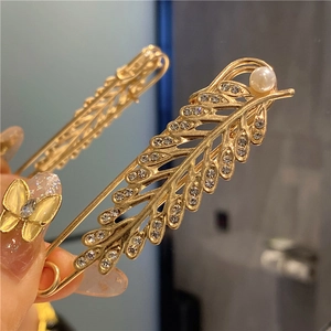 Detailed macro view of two gold leaf brooches with rhinestones and faux pearls