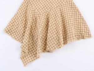 Détail de mini-jupe à carreaux avec ourlet asymétrique et bords en dentelle délicate
