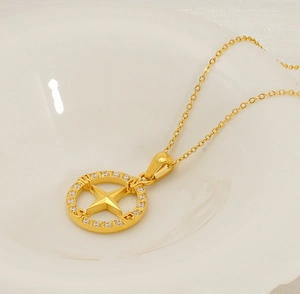 Detail of gold compass pendant with white zircons and star motif on white porcelain
