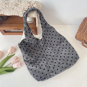 Dettaglio della borsa tote in velluto grigio a pois neri in un ambiente accogliente