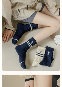 Dettaglio di calze in cotone a righe blu scuro e crema con ricamo di un coniglio
