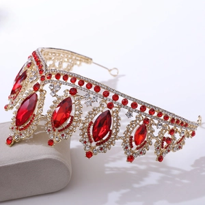 Close-up of golden baroque crown featuring large red crystals and sparkling rhinestones