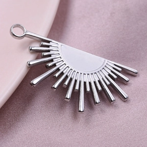 Macro shot of silver stainless steel sunburst fan pendant on soft pink satin fabric