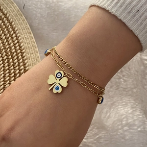 Detail of gold double-layer clover necklace with blue and white evil eye pattern on model