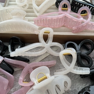 Macro shot of assorted colorful acrylic hair claw clips with golden springs on a display tray