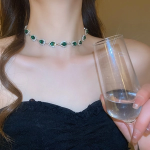 Macro shot of silver-tone teardrop necklace with green gems and halo crystal settings