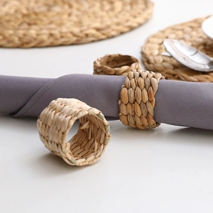 Macro shot of natural woven water hyacinth napkin rings on a purple fabric napkin