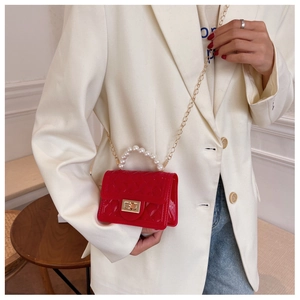 Detail of red quilted jelly bag with pearl handle and gold chain on neutral outfit
