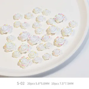 Detailed view of 3D resin camellia nail charms with white aurora pearlescent finish