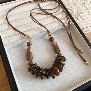 Detail of bohemian wood bead and coconut shell pendant necklace on white jewelry box