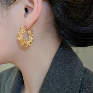 Gros plan d'une boucle d'oreille créole torsadée en plaqué or avec zircone sur un modèle