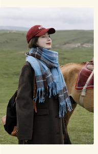 Blue plaid tassel scarf on model with red cap in scenic outdoor field setting
