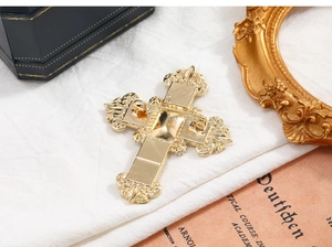 Detailed back view of a gold cross brooch with double safety pins on vintage decor