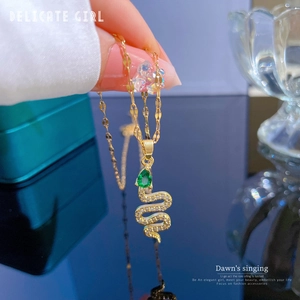 Close-up of gold snake pendant necklace with green drop gemstone and micro-pave zircons