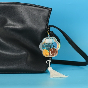 Close-up of acrylic milk bottle keychain with white tassel on black leather bag