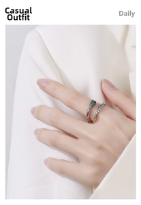 Detail view of silver snake ring with green zircon eyes on woman's finger