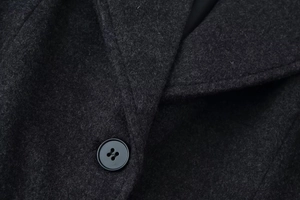 Macro shot of notch lapels and black button on a dark grey wool coat with fine texture