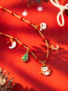 Detailed view of Christmas charms necklace with snowman and reindeer on red background