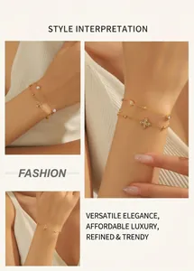 Detail of gold chain bracelet with pearl and rhinestone clover charm worn on wrist