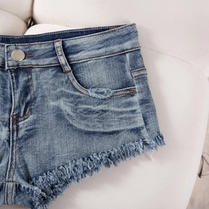 Detail der blauen Denim-Shorts mit ausgefranstem Saum und Distressed-Textur