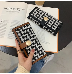 Detailed view of long houndstooth wallets in black and brown with golden metal clasps