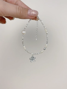 Detail of silver beaded bracelet with freshwater pearls and hollow flower pendant