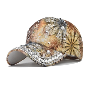 Detail of glitter baseball cap featuring rhinestone edges and colorful feather prints