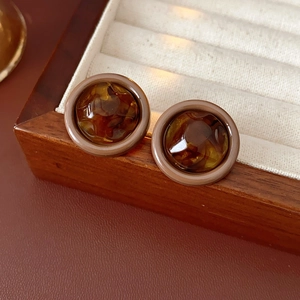 Detail of amber tortoiseshell resin round stud earring on a vintage wood jewelry box