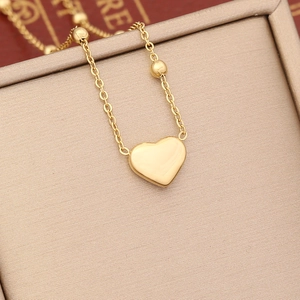 Close-up of golden heart pendant necklace with beaded chain on elegant jewelry box display