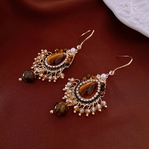 Détail de boucles d'oreilles vintage avec pierre œil de tigre et cristaux sur crochets