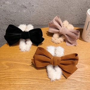 Detail of plush velvet bow hair clips in black, pink and brown on wooden surface