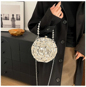 Detail of silver rose metallic handbag with beaded handle and chain strap on person