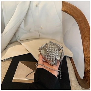 Detailed view of silver fish-shaped evening bag featuring engraved scale textures and chain