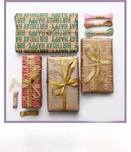 Flat lay of Happy Birthday kraft wrapping paper rolls with ribbons and colorful twine